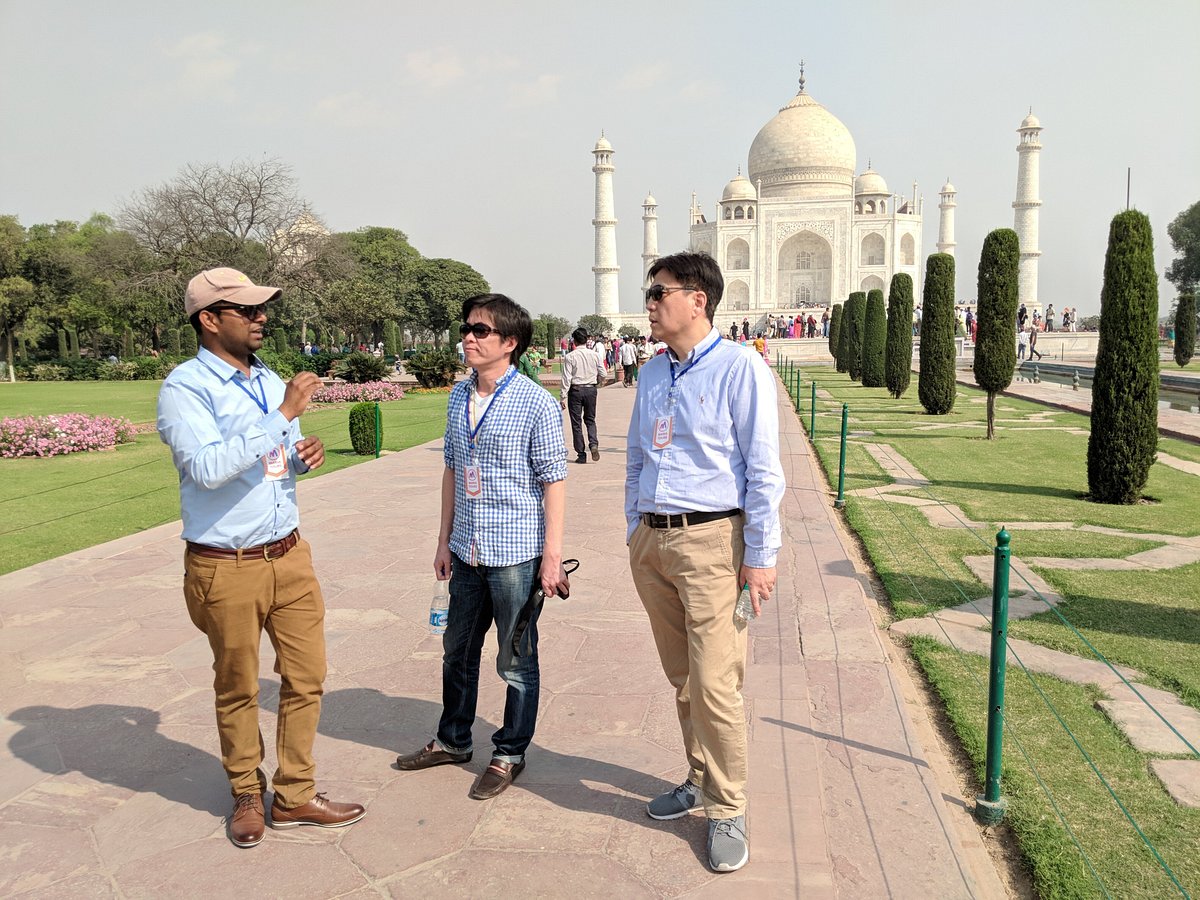 Two travelers walking the central path towards the Taj Mahal in the morning light