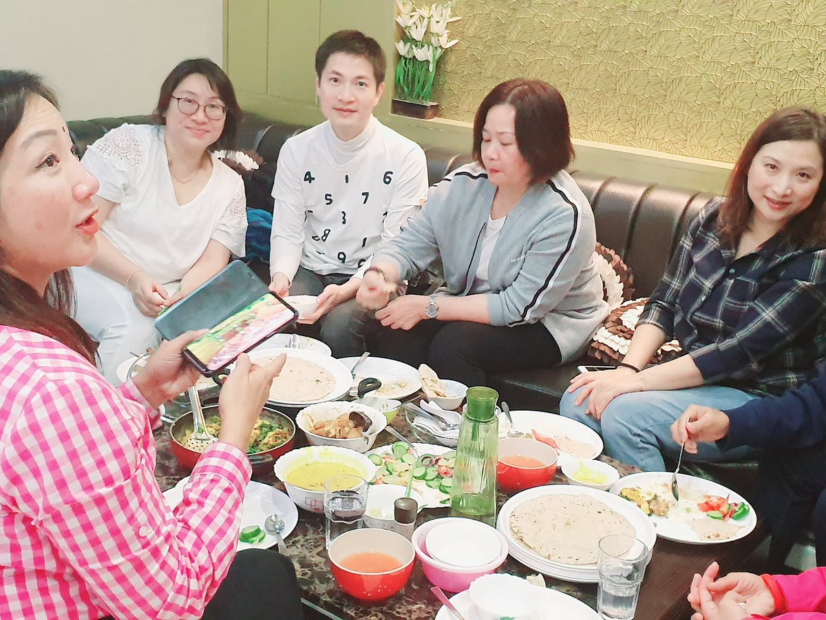 A group sharing a home-style Indian meal of curries, dal and fresh roti